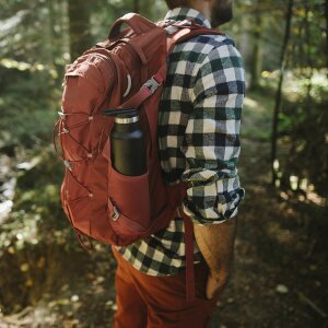 Ein Mann mit Rucksack und Trinkflasche im Wald beim Wandern.
