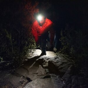Ein Mann mit Stirnlampe wandert im dunkeln.