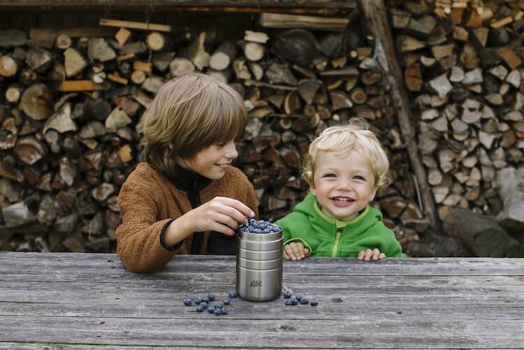 Zwei Kinder essen Blaubeeren aus einem Esbit Thermobecher 